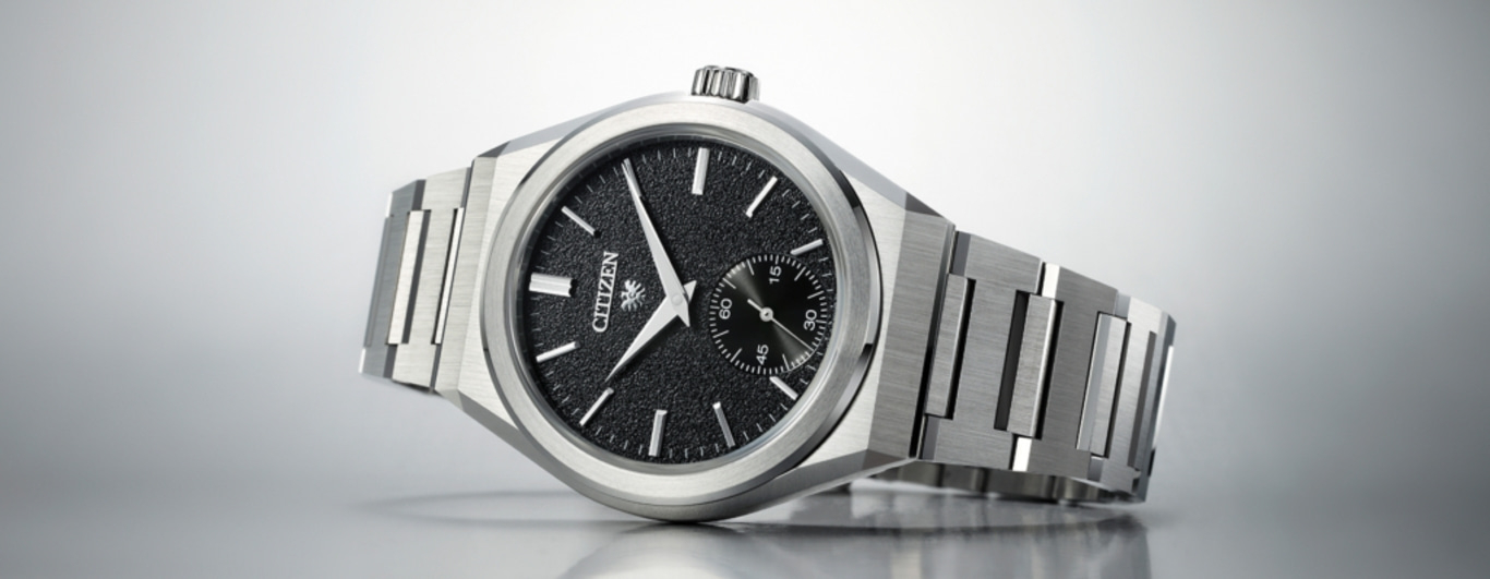 Citizen-Uhr mit schwarzem Zifferblatt und silbernem Armband auf reflektierender Oberfläche