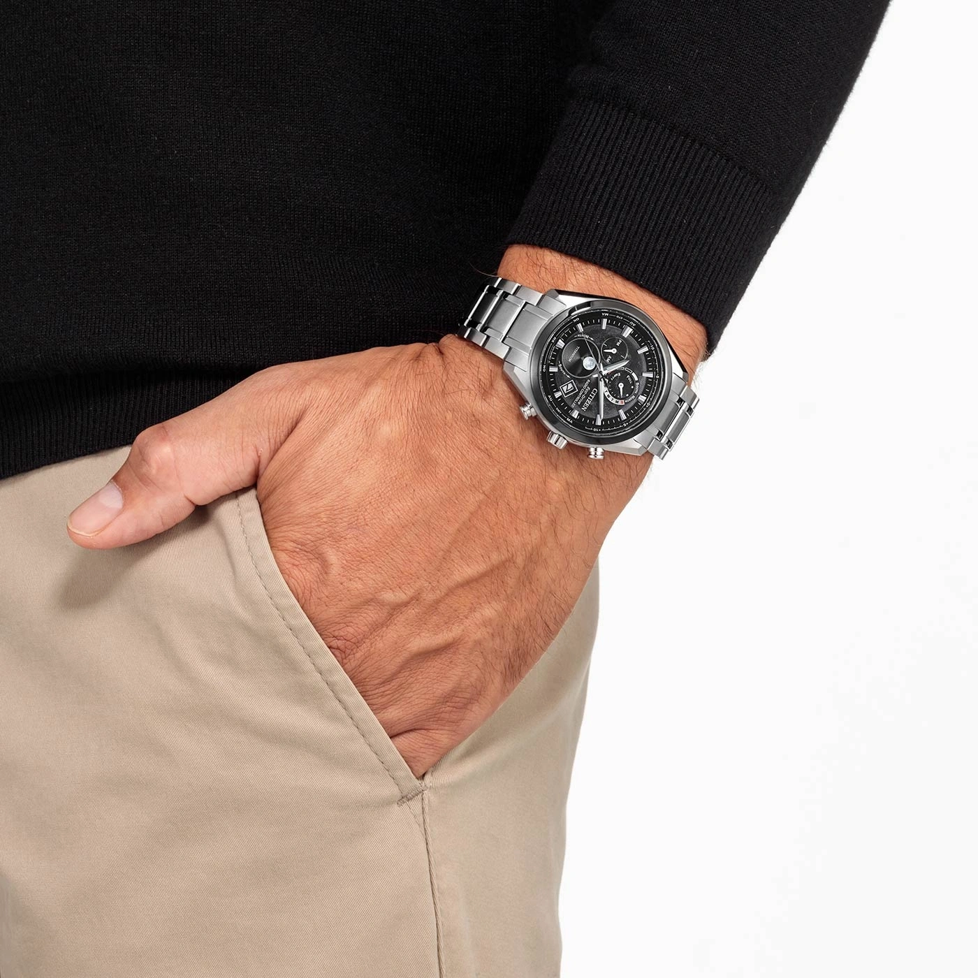 Mann mit Uhr, Hand in der Tasche, schwarzer Pullover, beige Hose