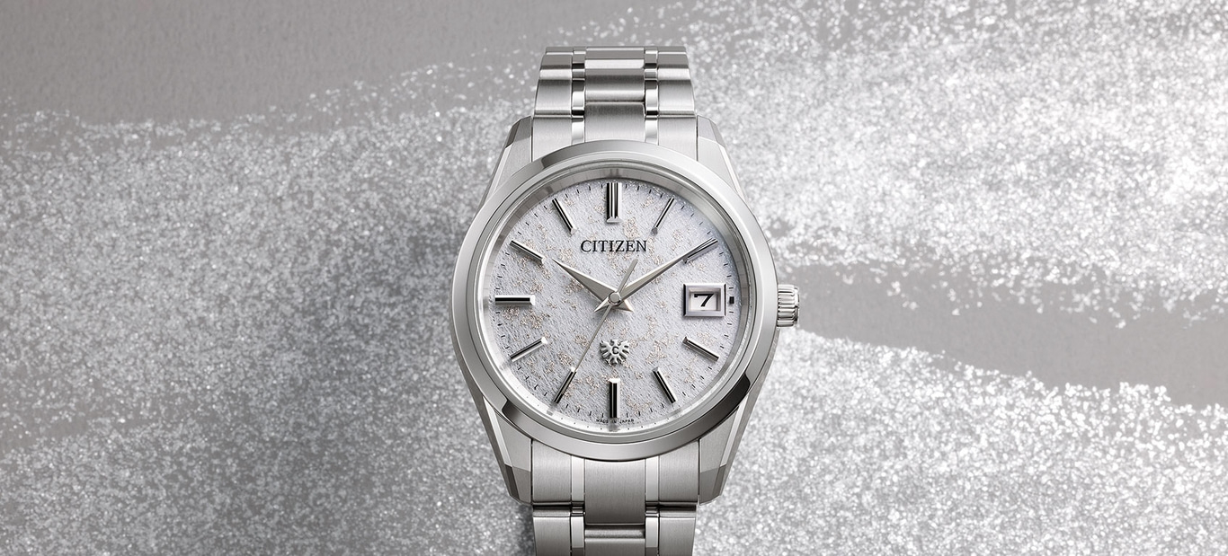 A Citizen watch with a silver metal bracelet and textured white dial is displayed on a shimmering background.
