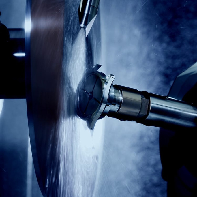 Metallbearbeitungsprozess mit rotierendem Werkzeug und Wasserspray, Nahaufnahme.