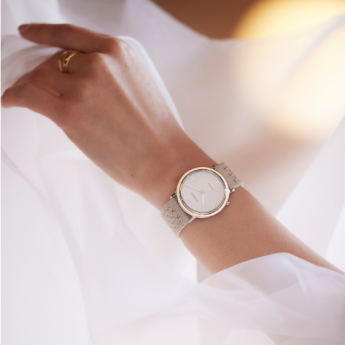 Nahaufnahme einer Armbanduhr mit beigem Armband am Handgelenk einer Frau.