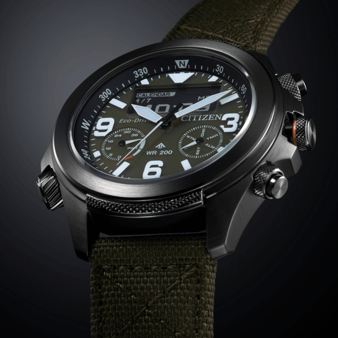 Citizen-Uhr mit Digitalanzeige, olivgrünem Armband und schwarzem Gehäuse, zeigt Zeit und Datum.