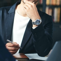 Mann im Anzug mit Uhr, hält Stift, denkt nach, Geschäftstreffen, Büro