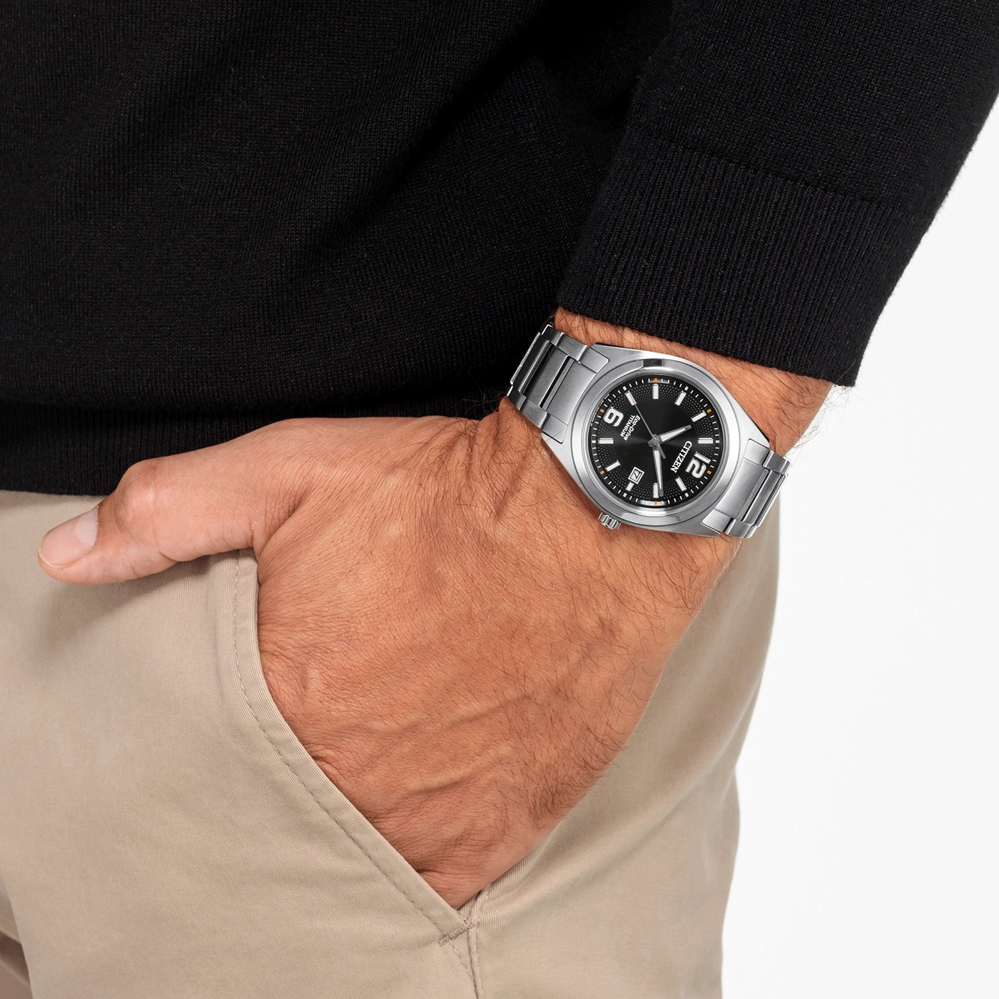 Mann mit Citizen-Uhr, schwarzem Pullover und beigefarbener Hose.