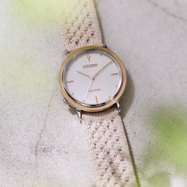 Citizen-Uhr mit cremefarbenem Armband auf strukturierter Oberfläche