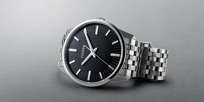 This image features a sleek Citizen watch with a black dial and a polished silver-toned case and metal bracelet. It has clean, modern applied hour markers and slender hands, exuding a minimalist and sophisticated aesthetic.