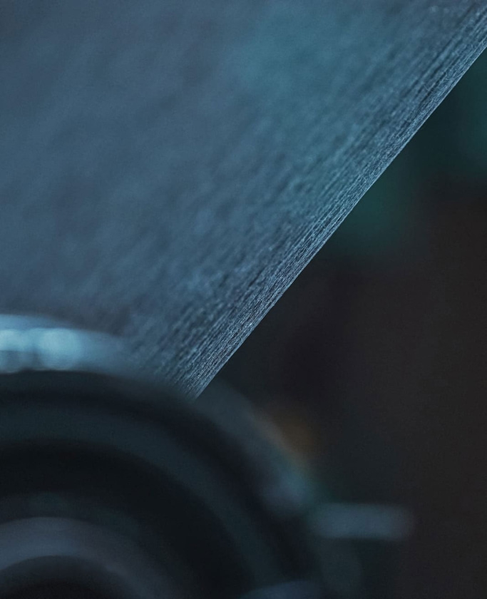 Nahaufnahme von strukturiertem Papier mit dunklem, verschwommenem Hintergrund und weicher Beleuchtung.