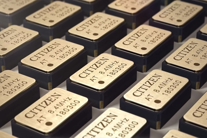 This image shows a grid of numerous small, rectangular electronic components, each labeled 'CITIZEN AT 8.4MHz 180300' on a golden-toned top. They appear to be precision quartz oscillators, emphasizing uniformity and technological precision.
