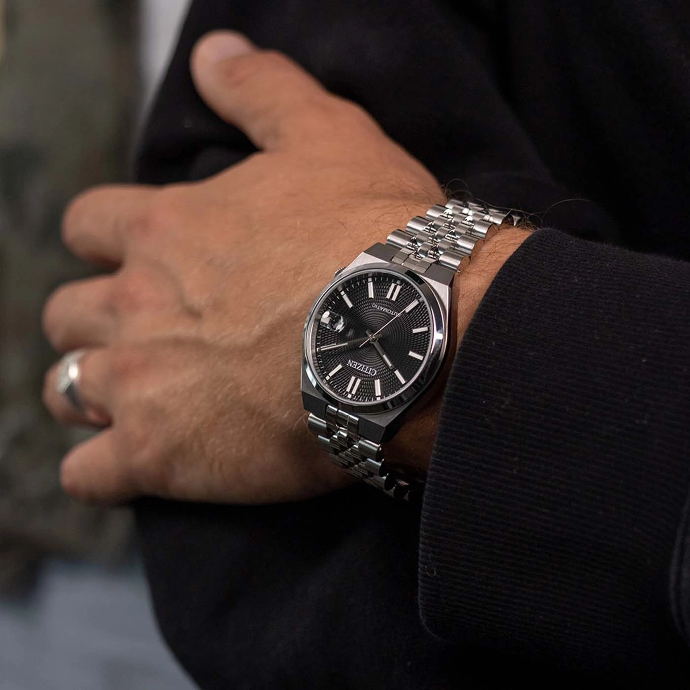 Ein Mann trägt eine Citizen Automatik-Uhr am linken Handgelenk.