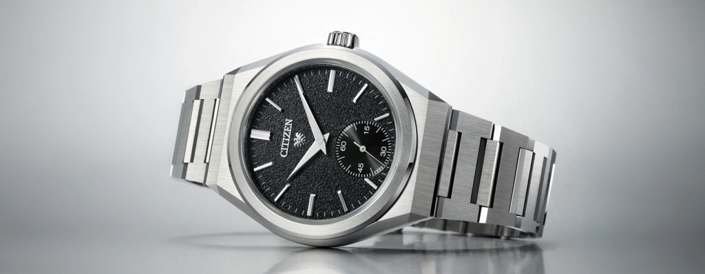 Citizen-Uhr mit schwarzem Zifferblatt und silbernem Armband auf reflektierender Oberfläche