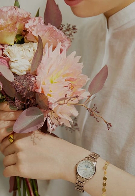 Frau hält Blumen, trägt Uhr und Armband, Nahaufnahme