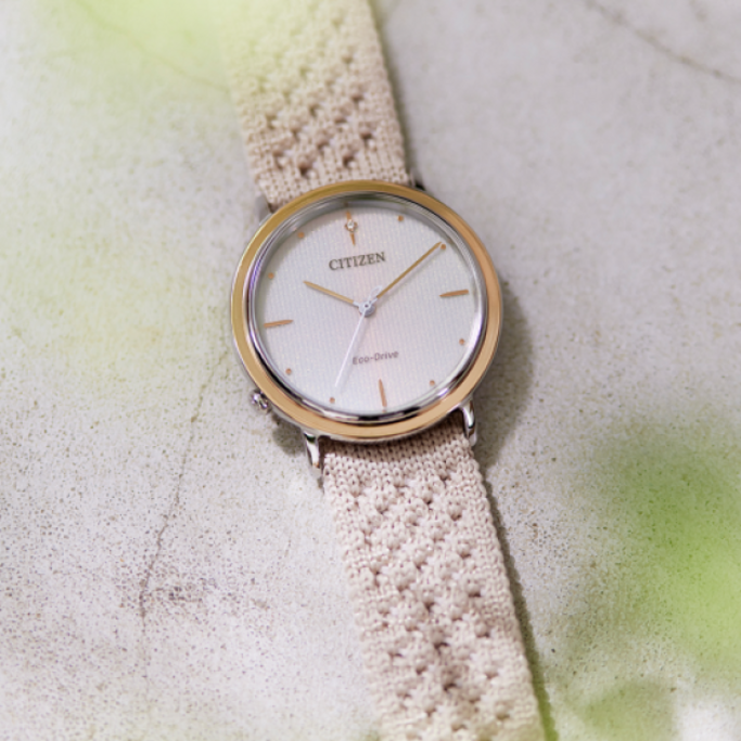 Citizen-Uhr mit cremefarbenem Armband auf strukturierter Oberfläche