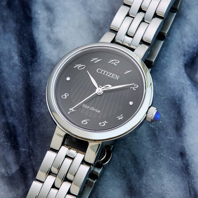 Citizen-Uhr mit dunklem Zifferblatt und silbernem Armband auf Marmoroberfläche.