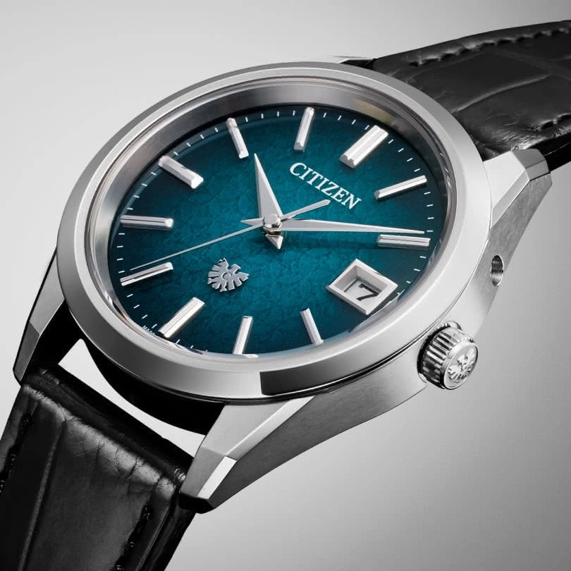Citizen-Uhr mit tealfarbenem Zifferblatt, silbernem Gehäuse und schwarzem Lederarmband.