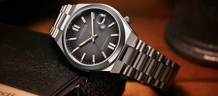 Citizen-Uhr mit schwarzem Zifferblatt und silbernem Armband auf einem Buch