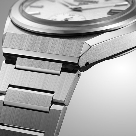 Nahaufnahme einer silbernen Uhr mit gebürsteter Metalloberfläche und weißem Zifferblatt.