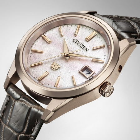 Citizen-Uhr mit weißem Zifferblatt, goldenen Zeigern und Lederarmband. Elegantes Design.