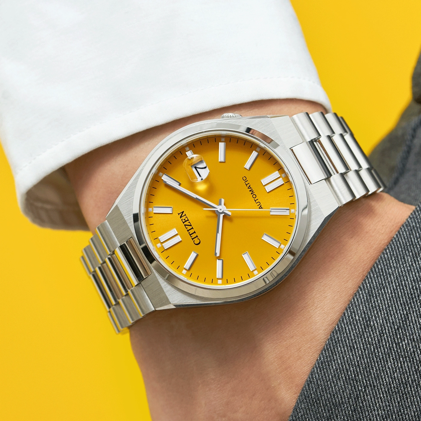 Citizen-Uhr mit gelbem Zifferblatt und silbernem Armband am Handgelenk
