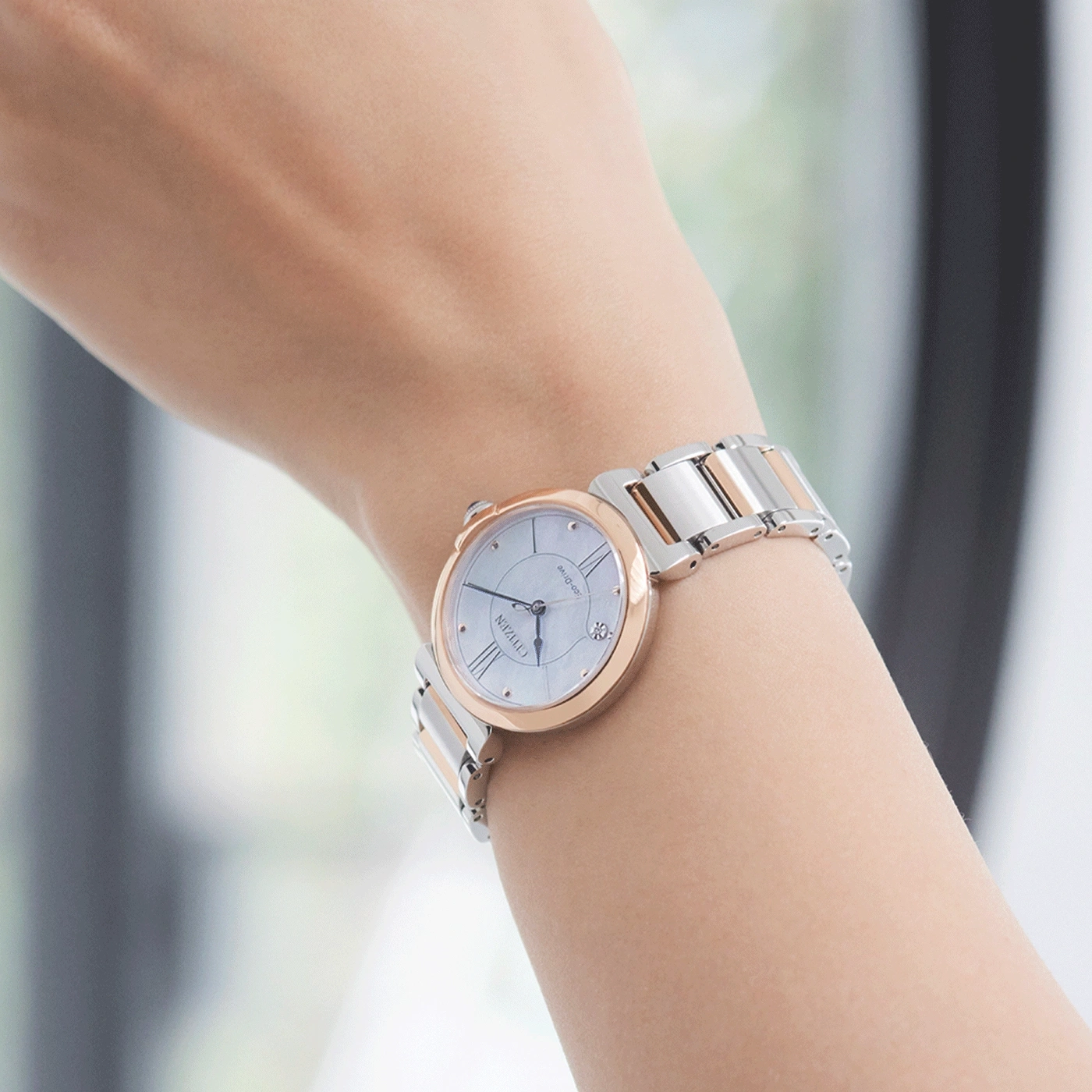 Armbanduhr mit silbernem und roségoldenem Band am Handgelenk