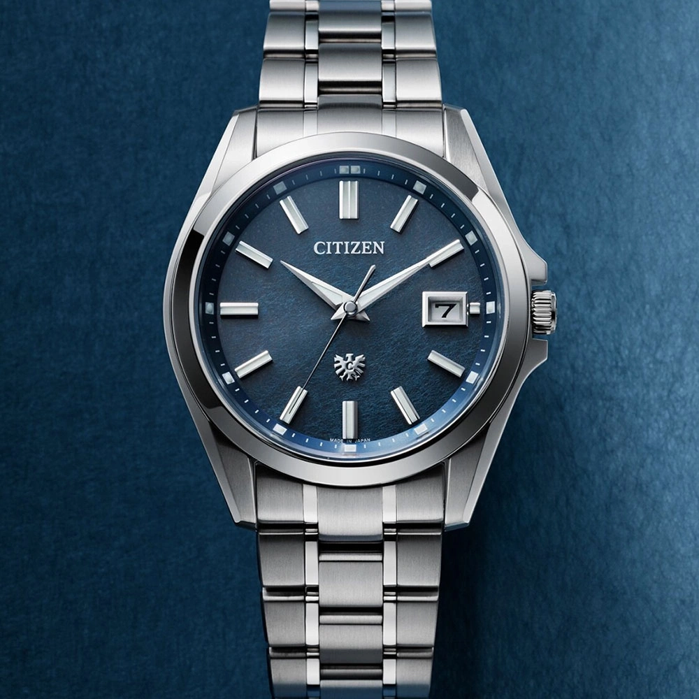 Citizen-Uhr mit blauem Zifferblatt und silbernem Armband auf blauem Hintergrund.