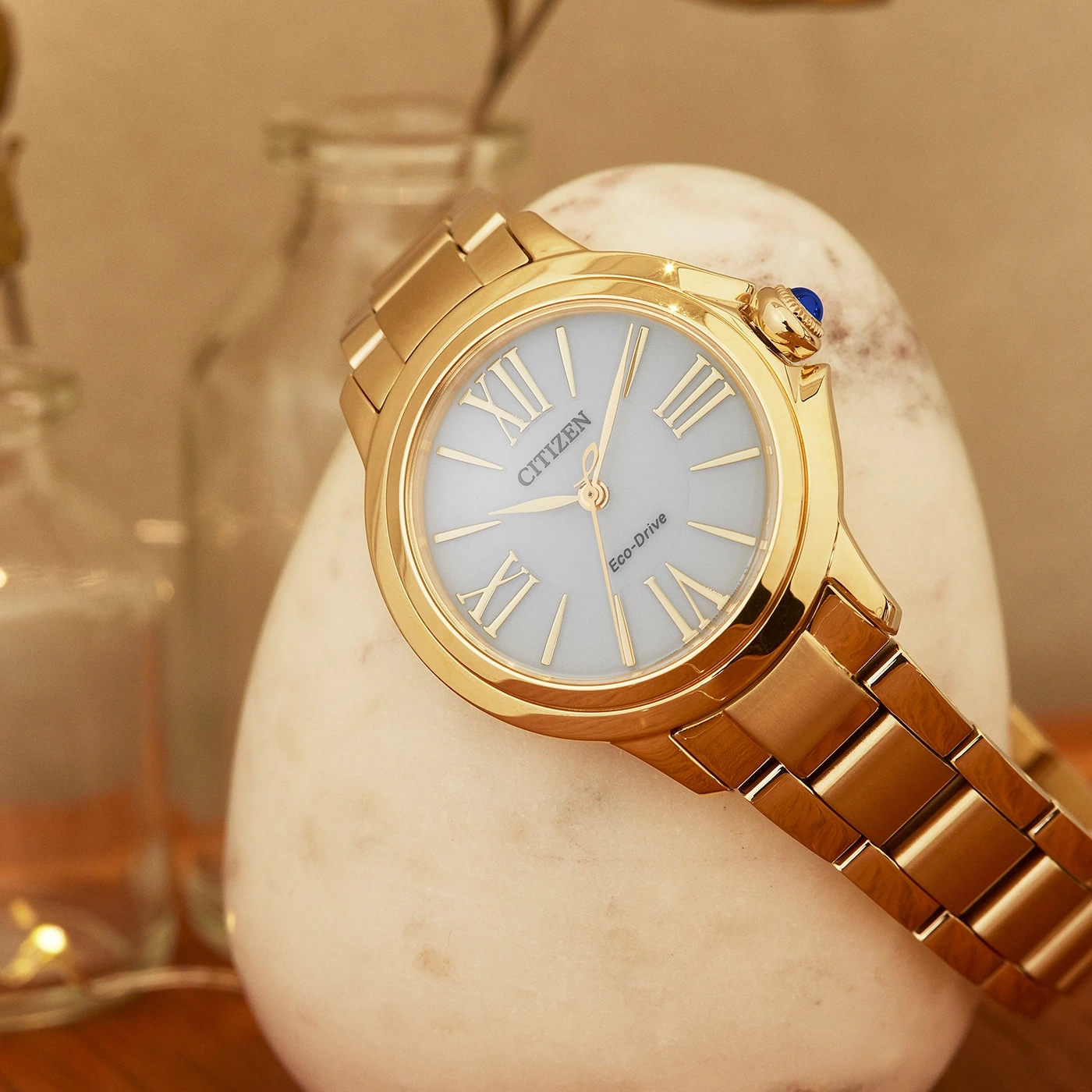 Goldene Citizen-Uhr mit hellblauem Zifferblatt auf einem weißen Stein