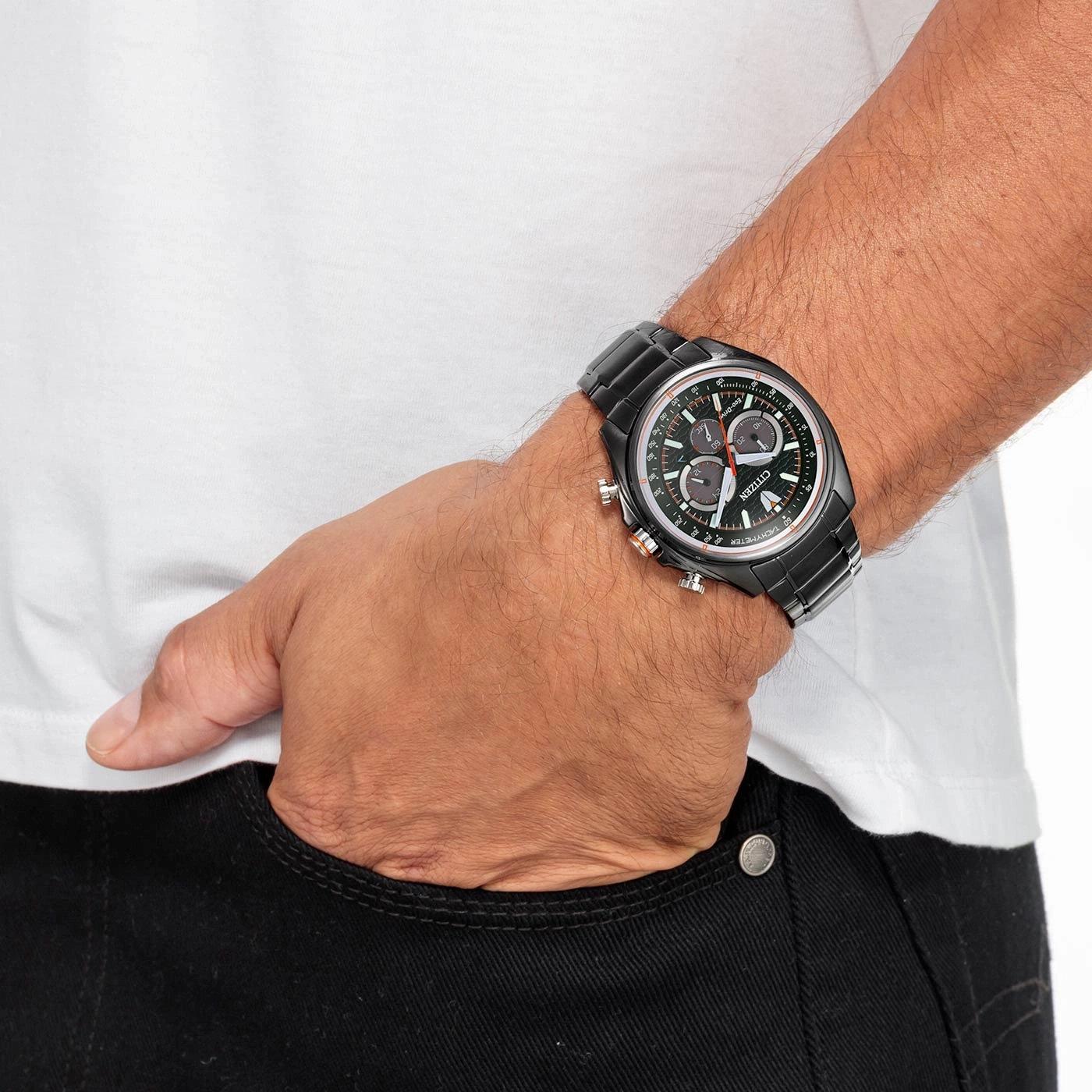 Mann mit schwarzer Citizen-Uhr, Hand in der Tasche, weißes Hemd, schwarze Jeans.