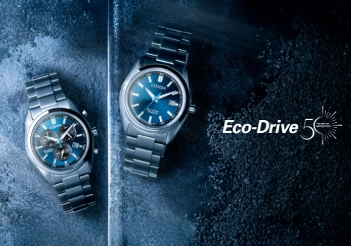 Zwei blaue Citizen Eco-Drive Uhren, eine mit Chronograph, auf dunkler Texturoberfläche.