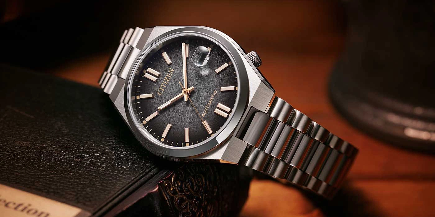 Citizen Automatikuhr mit schwarzem Zifferblatt und silbernem Armband.