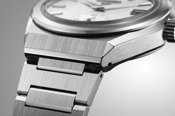 Nahaufnahme einer silbernen Uhr mit gebürsteter Metalloberfläche und detailliertem Design.