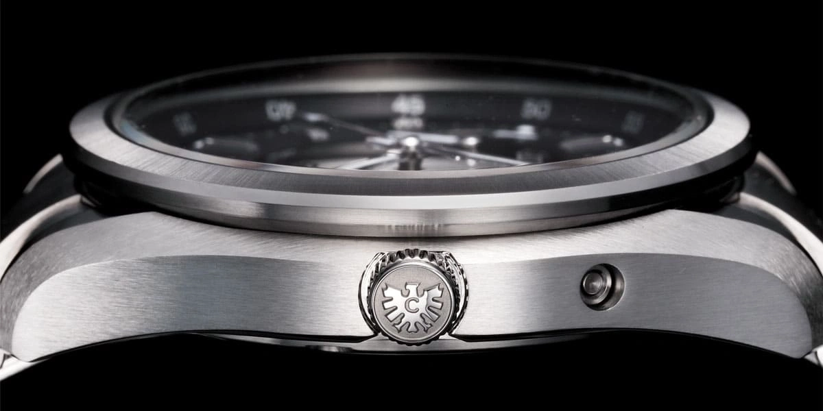 Nahaufnahme einer silbernen Uhr mit schwarzem Zifferblatt und komplizierten Details.