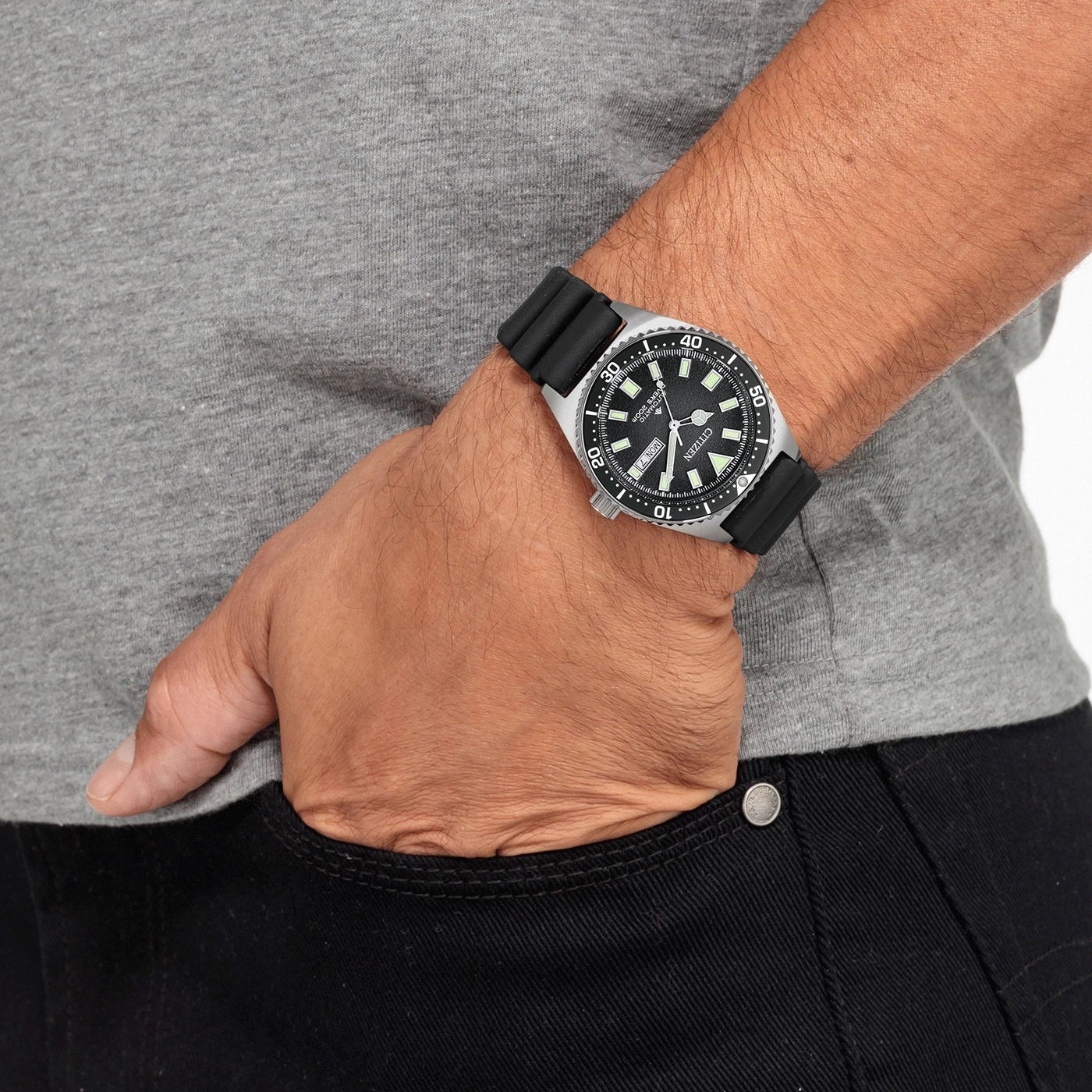 Mann mit Citizen-Uhr und schwarzem Armband, Hand in der Hosentasche.