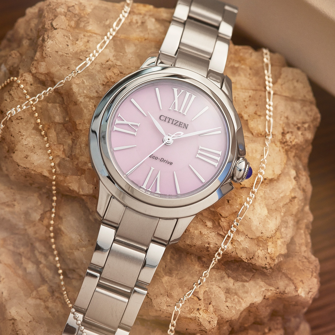 Citizen-Uhr mit rosa Zifferblatt und silbernem Armband, mit Schmuck.