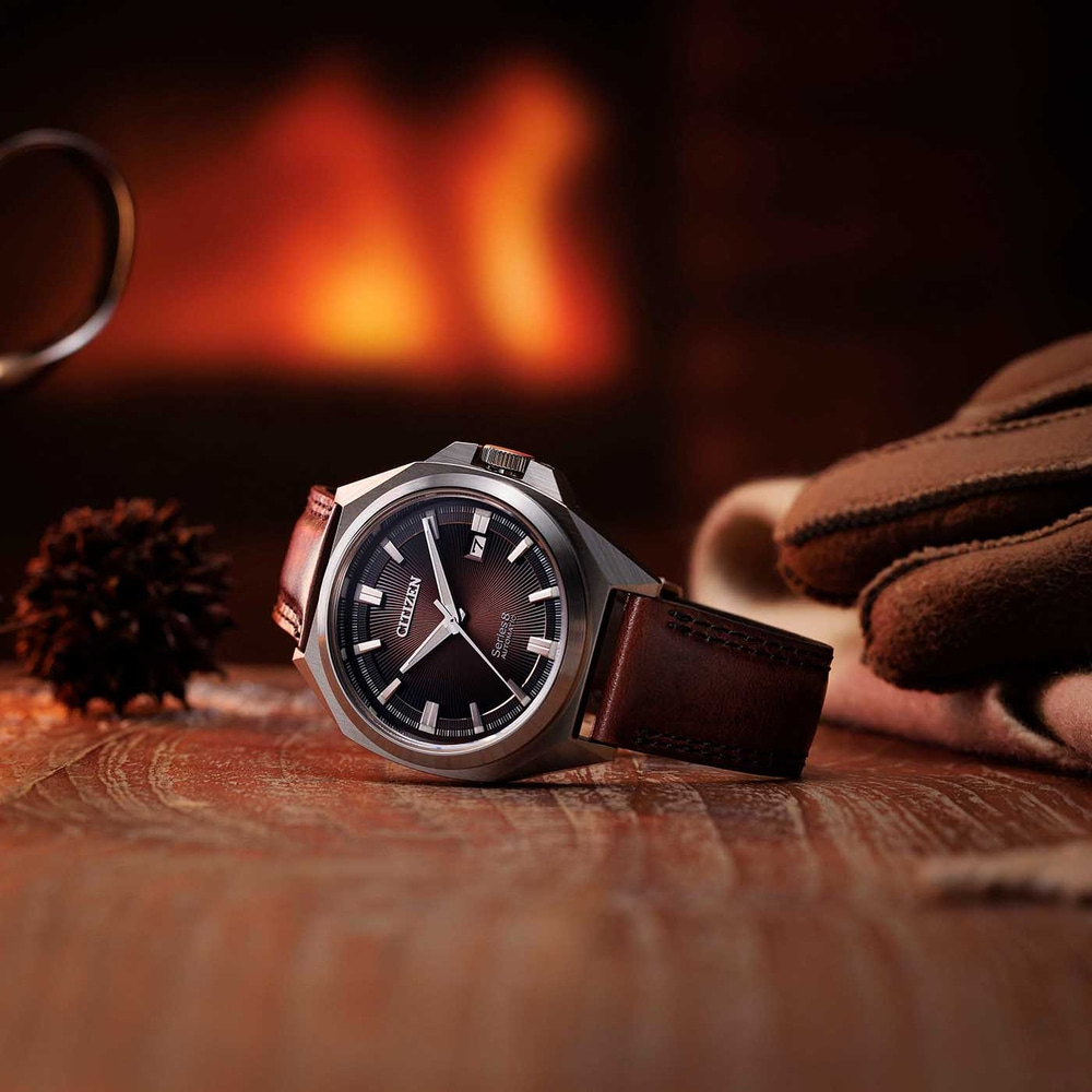 Citizen-Uhr auf Holztisch mit Kaminhintergrund und Handschuhen