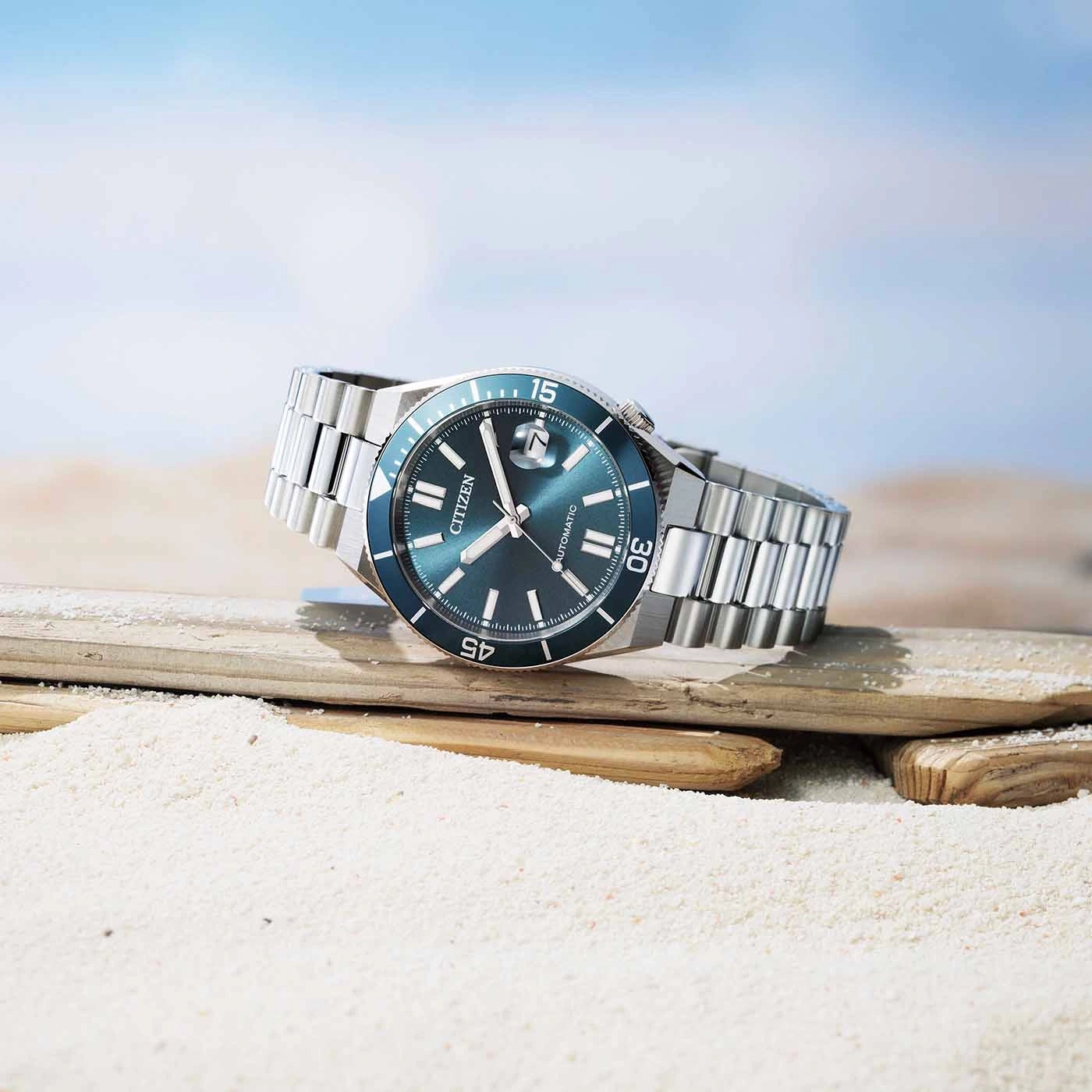 Eine Citizen Automatik-Uhr ruht auf Treibholz an einem Sandstrand.