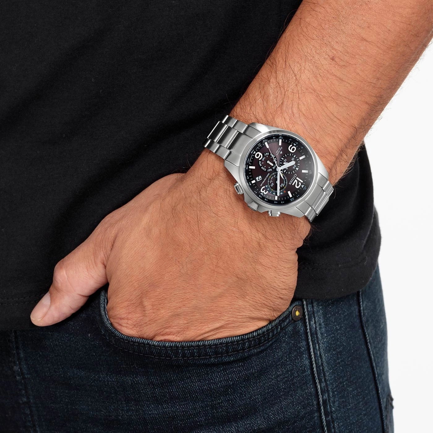 Mann trägt silberne Uhr, schwarzes Hemd und blaue Jeans.