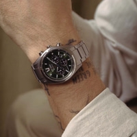 Ein Mann trägt eine silberne Citizen Eco-Drive Uhr mit grünem Zifferblatt.