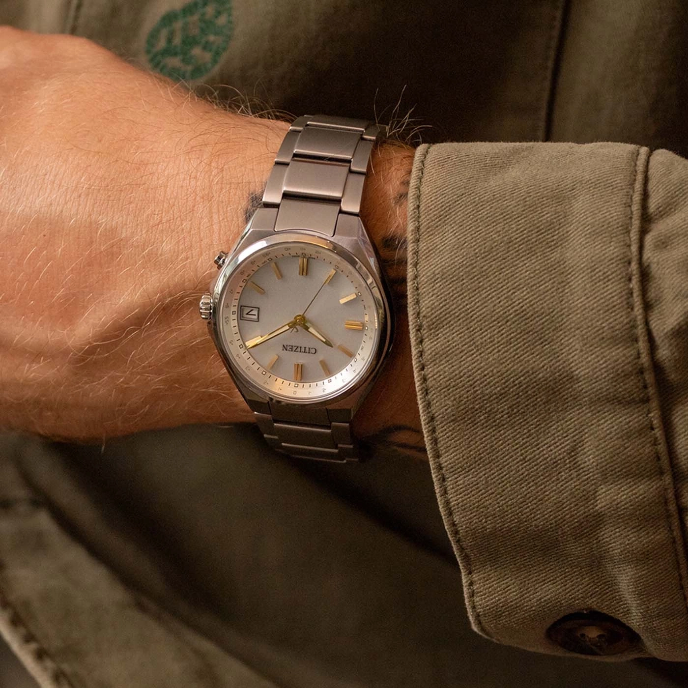 Herrenarmbanduhr am Handgelenk, Marke Citizen, silbernes Band und helles Zifferblatt.