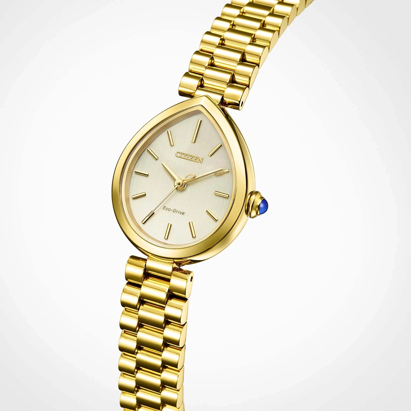 Eine Nahaufnahme eines goldenen Citizen Eco-Drive-Uhr mit tropfenförmigem Zifferblatt und einem blauen Edelstein auf der Krone im Studio.