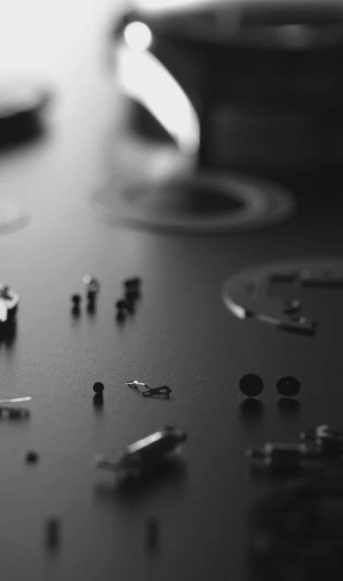 Uhrenteile auf dunkler Oberfläche verstreut, monochrom, Nahaufnahme.