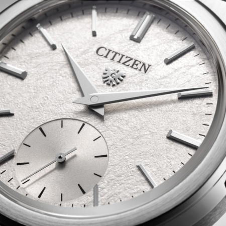 This close-up shows a Citizen watch with a textured white dial, silver hands, and a sub-seconds dial.