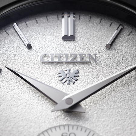 This close-up shows a Citizen watch's brushed silver case, textured white dial, and black leather strap connection.