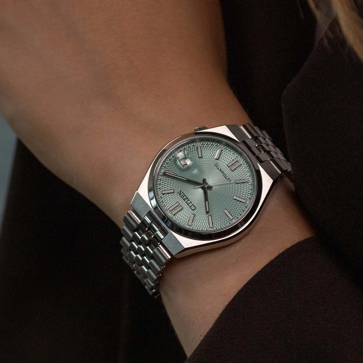 Eine Person trägt eine Citizen Automatik-Uhr mit mintgrünem Zifferblatt.