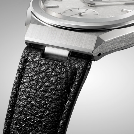 This close-up shows a Citizen watch's brushed silver case, textured white dial, and black leather strap connection.