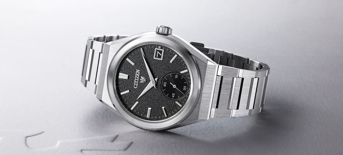 Citizen-Uhr mit schwarzem strukturiertem Zifferblatt und silbernem Armband.